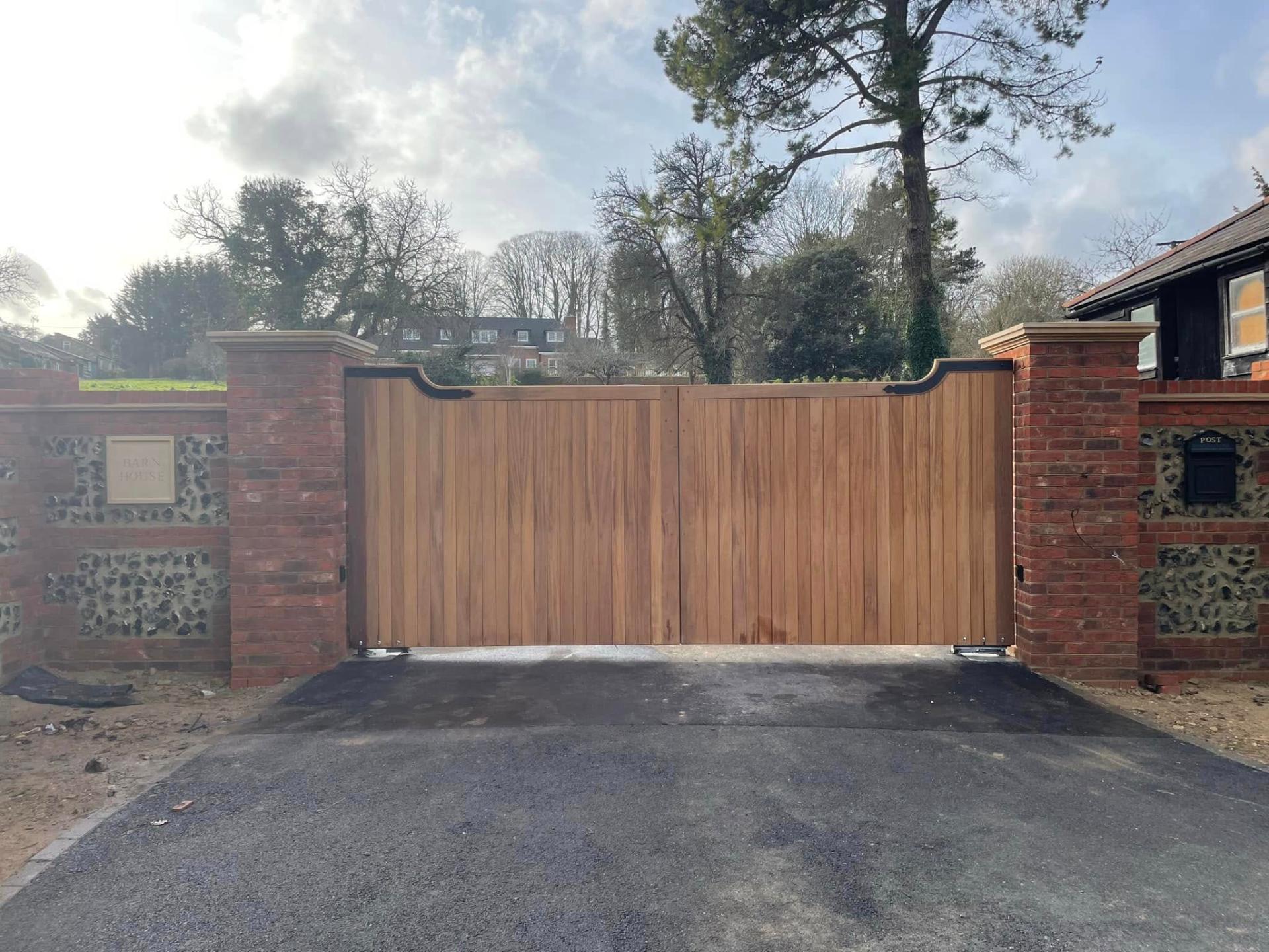 tarmac driveway with brick pillars and wooden gates