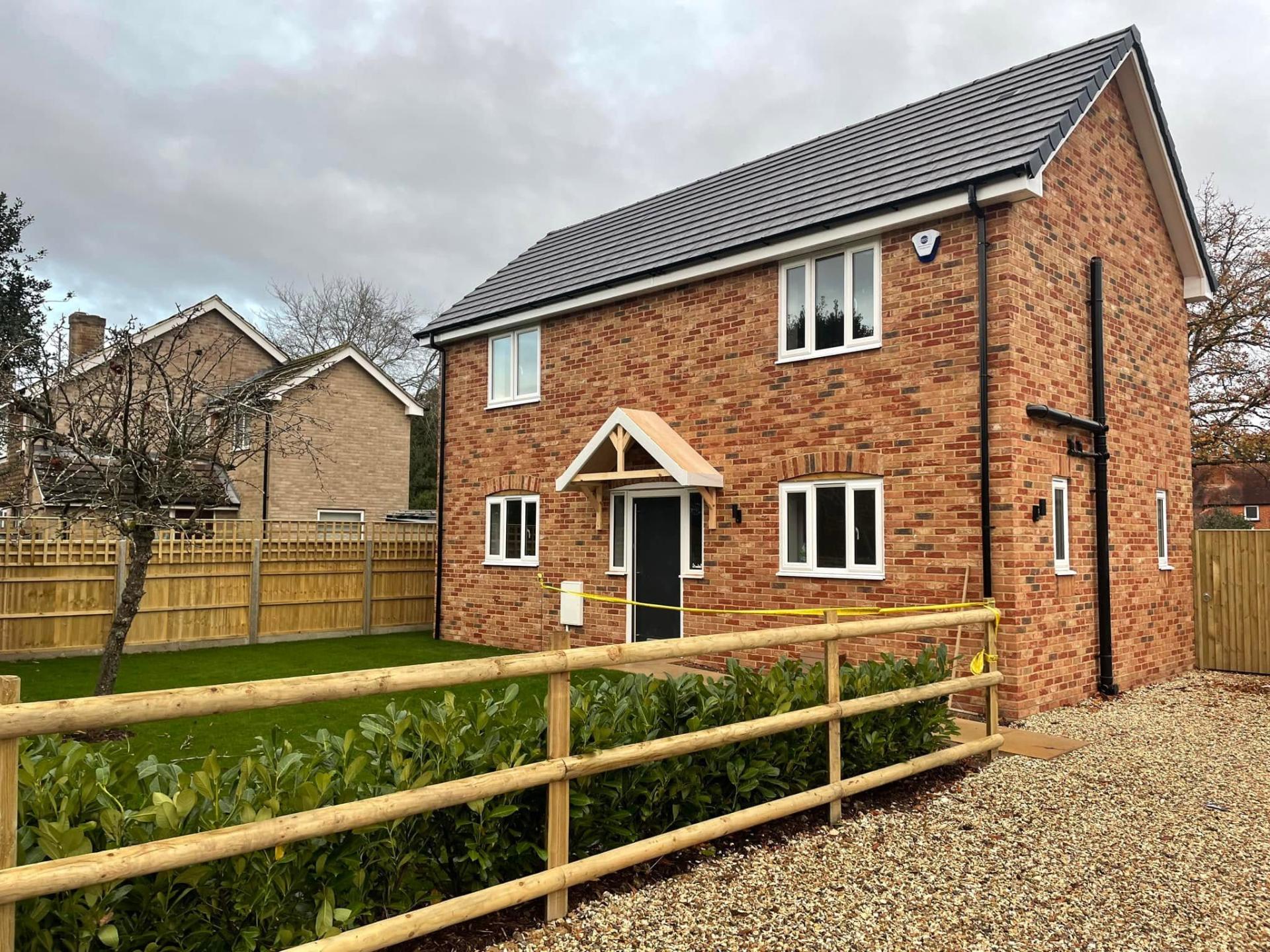 New build house showing lawn, gravel driveway, and fences