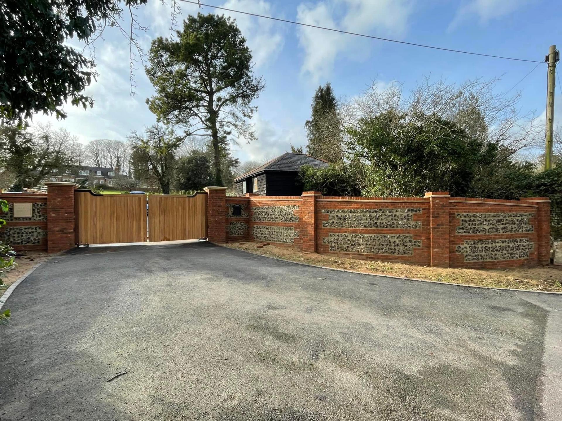 tarmac driveway with brick and flint wall and gates