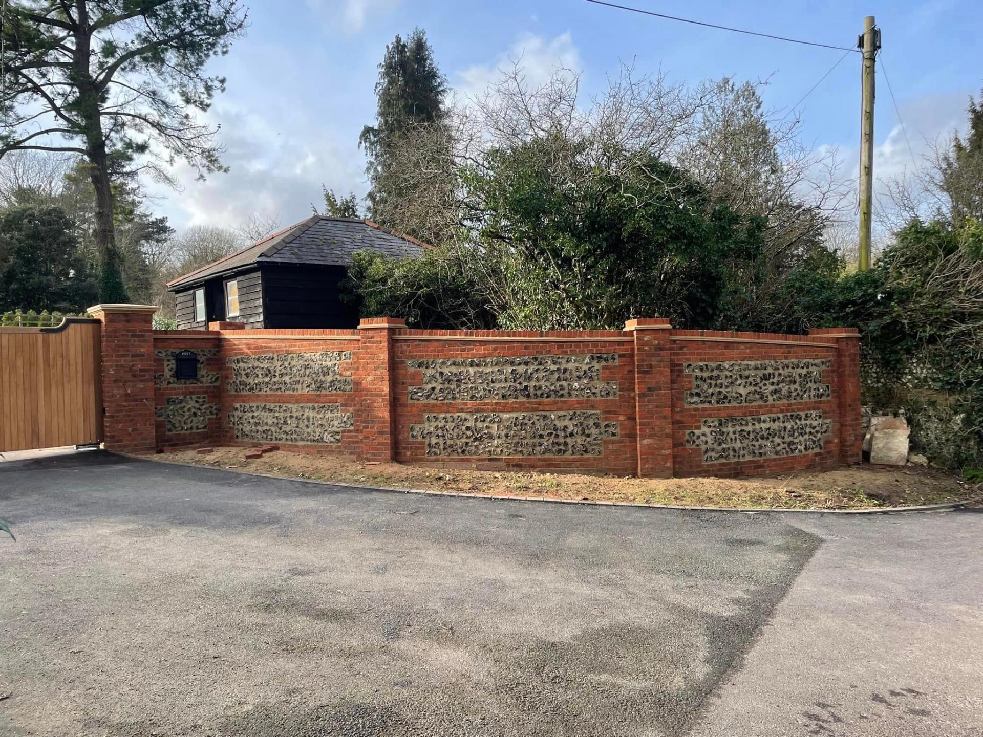new brick and flint wall with wooden gate and tarmac drive