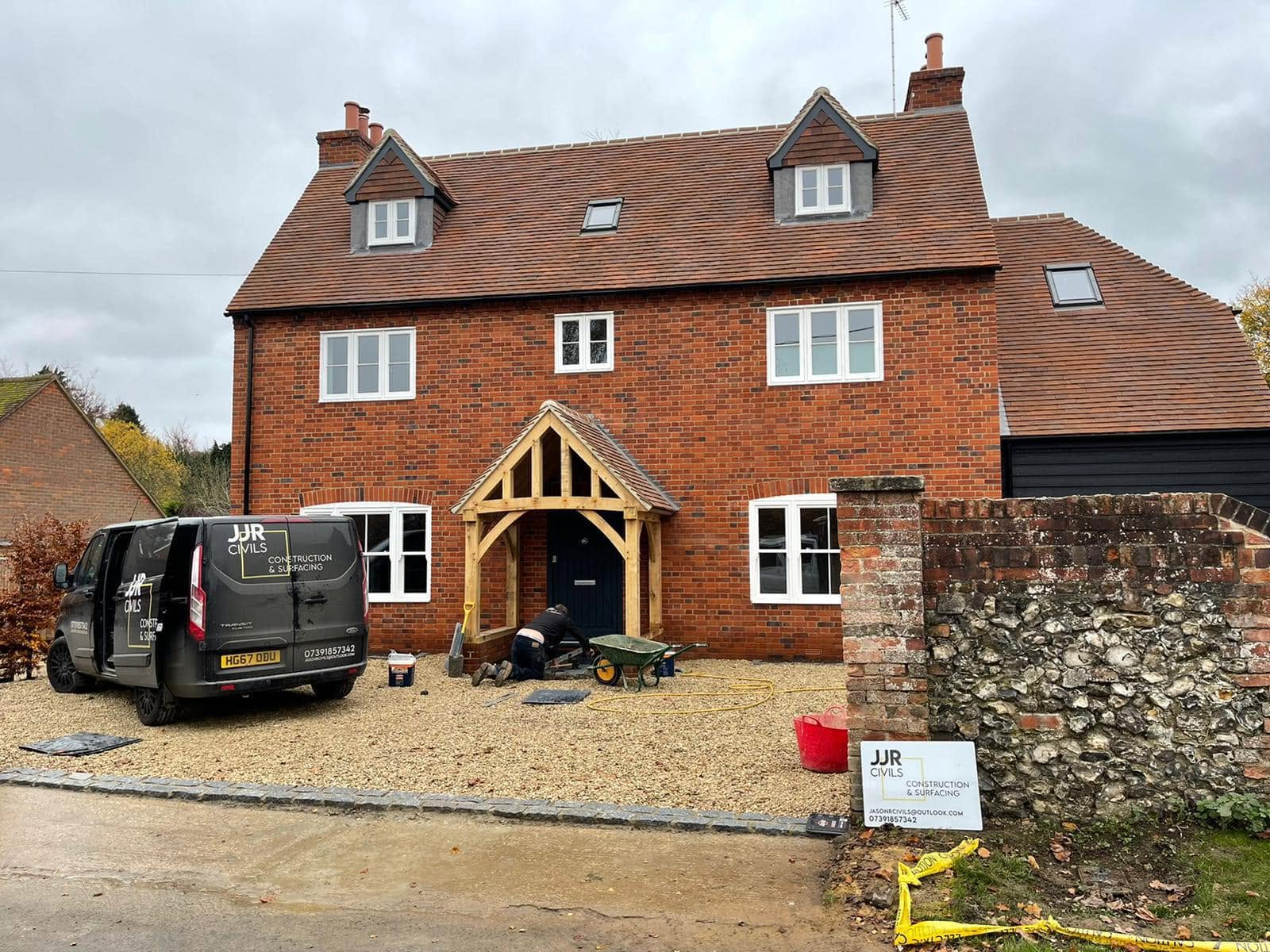 Gravel driveway in front of large red brick house